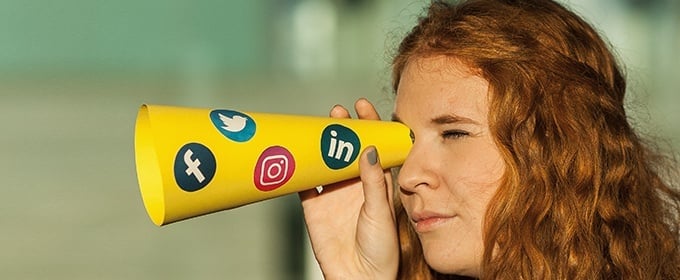 donna guarda attraverso un tubo con stampati sopra i loghi di diversi social media