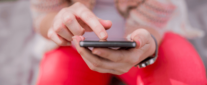 adolescente tiene in mano uno smartphone e tocca lo schermo con il dito