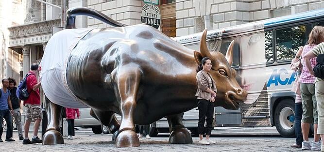 donna si fa fare una foto di fronte alla statua dorata di un toro che indossa delle mutande