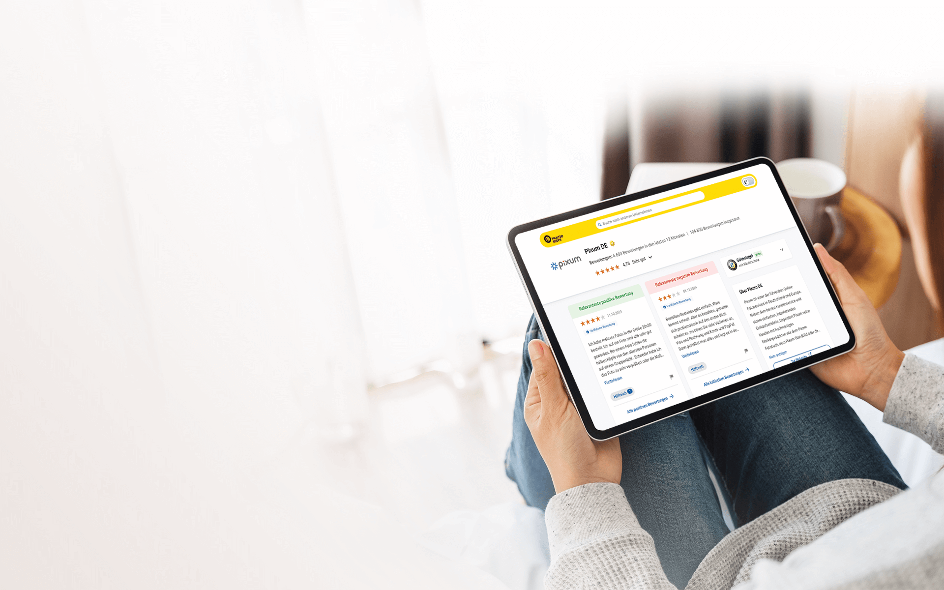 Persona sostiene un tablet dove si vede il profilo di recensioni di Pixum sul sito Trusted Shops 