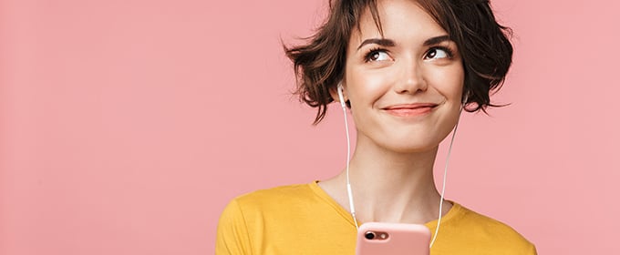 donna con cuffie e smartphone su sfondo rosa