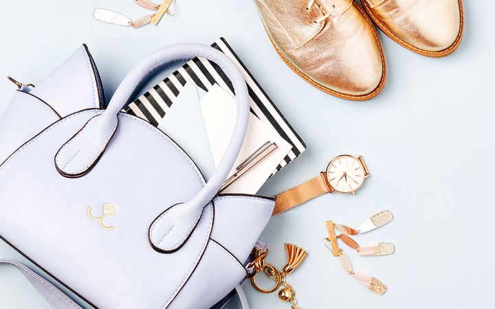 borsa, scarpe, orologio e gioielli su sfondo azzurro